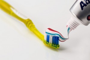 Photo of a yellow toothbrush with toothpaste being applied to it; for information on free teeth whitening in Plano, TX