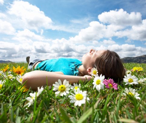 Photo of young woman lying in a field of trass and flowers for Plano sedation dentist Miranda Lacy DDS.
